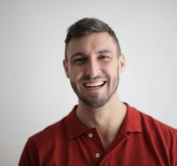 A cheerful man smiling broadly against a plain white background.