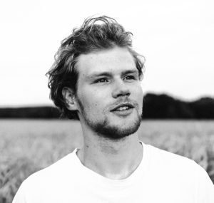 Black and white portrait of a man gazing away in a field.